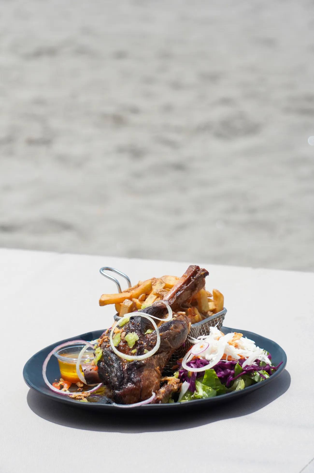 Souris d'agneau confite servie sur la plage, frites maison et salade
